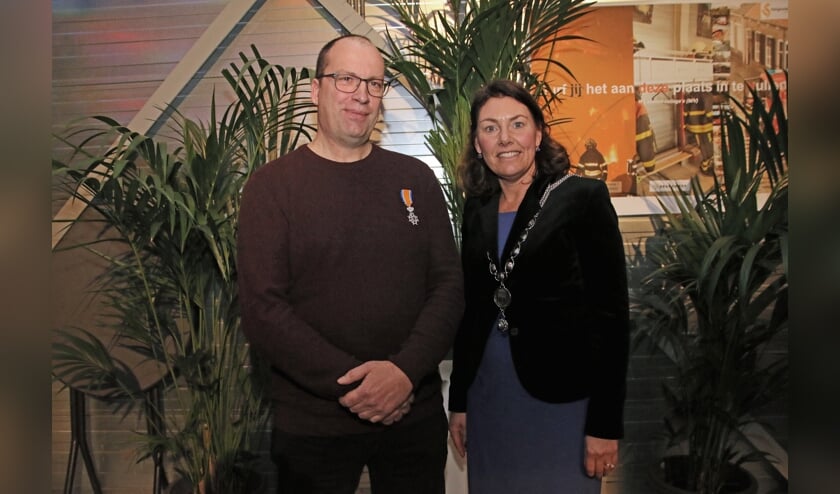 Brandweerman Mart Potter met zijn lintje en burgemeester Van Egmond met haar nieuwe ambtsketen. FOTO COBY WEIJERS