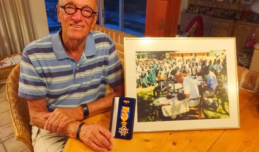 Bert Slingenberg met zijn onderscheiding en een foto van zijn ontwikkelingswerk.