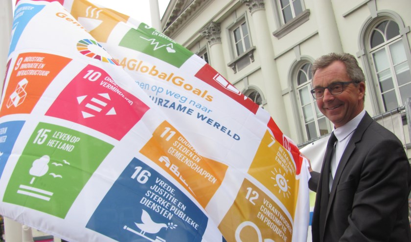Wethouder Johan de Beer hijst de Global Goals-vlag op de Markt in Zundert.