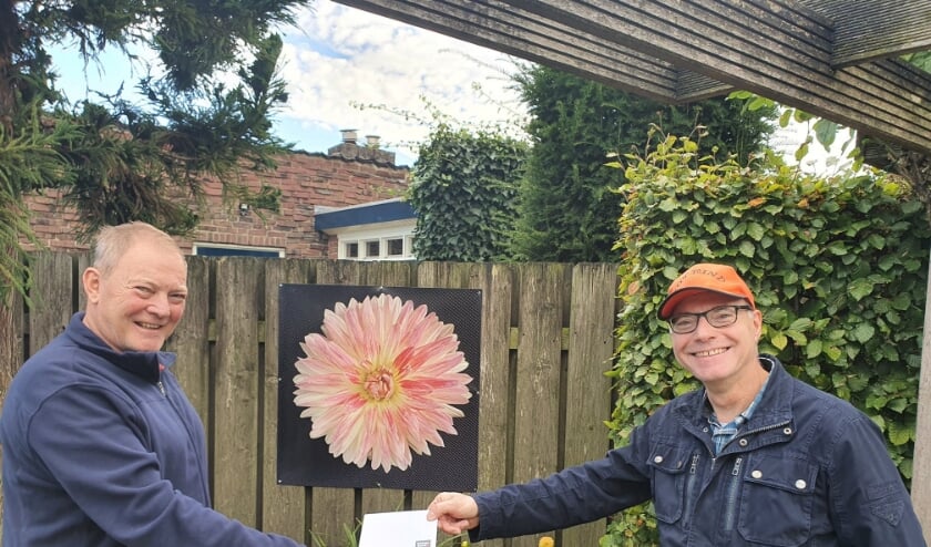 <p>Ed Nouws (L) en Marte Peemen (R) uitreiking van de prijs met op de achtergrond de bloem.</p>