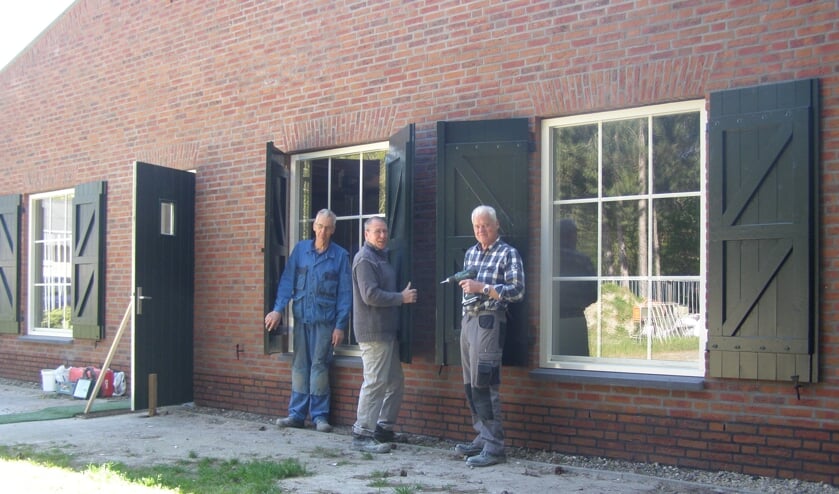 Leden van de vrijwilligersploeg plaatsen luiken aan de voorzijde van De Karkooi.