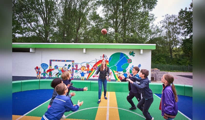 Kinderen op het voetbalcourt met de nieuwe muurschildering op de fietsenstalling.