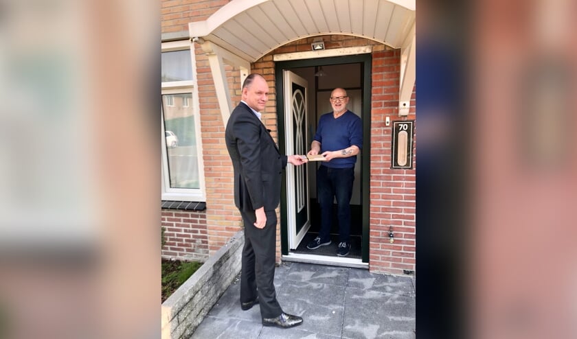 <p>Wethouder Kees Verburg overhandigt een kookboek aan een matelzorger.</p>
